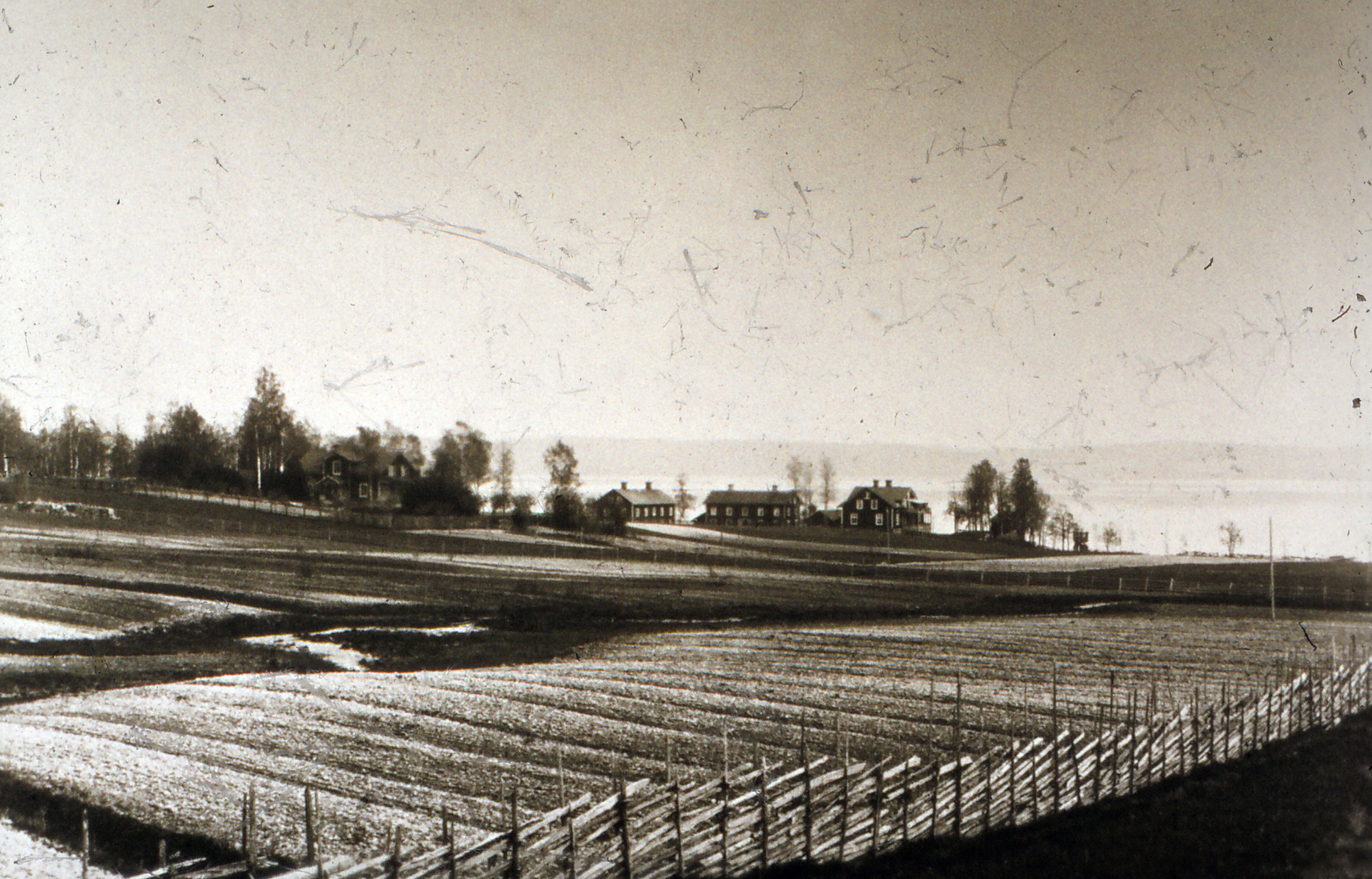 Vy över åkrar mot gården och sjön