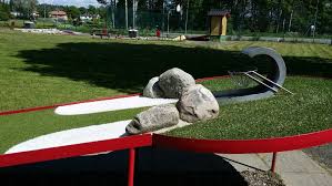 Närbild på minigolfklubba som slår en boll (illustrationsbild)